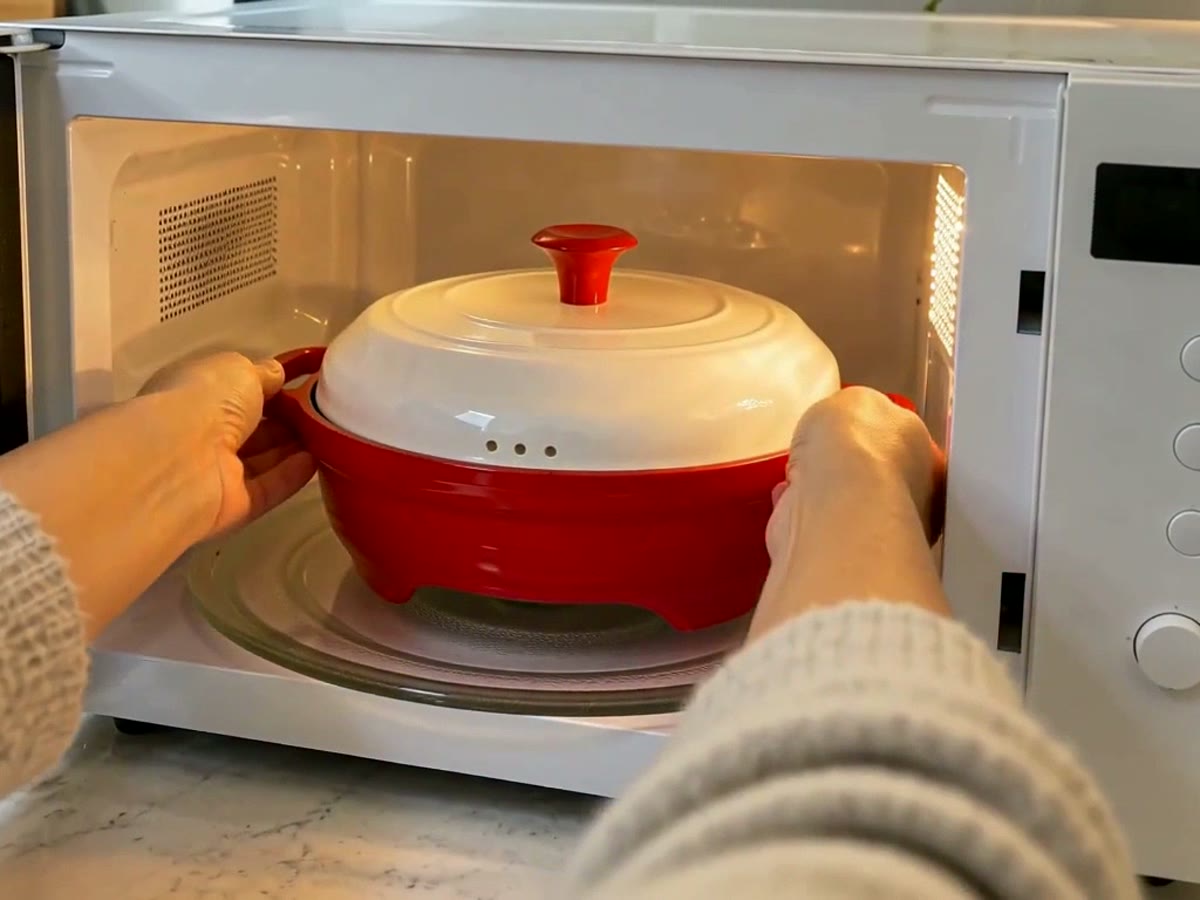 Placing the closed red grill pan into the microwave